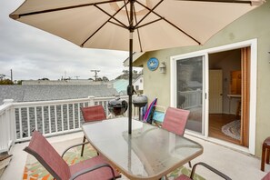 Un balcon avec une table en verre, des chaises, un barbecue et un parasol.