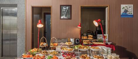A buffet table with various food items and a red lamp.