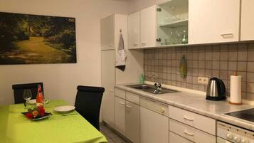A kitchen with a dining table, chairs, a sink, and a stove.