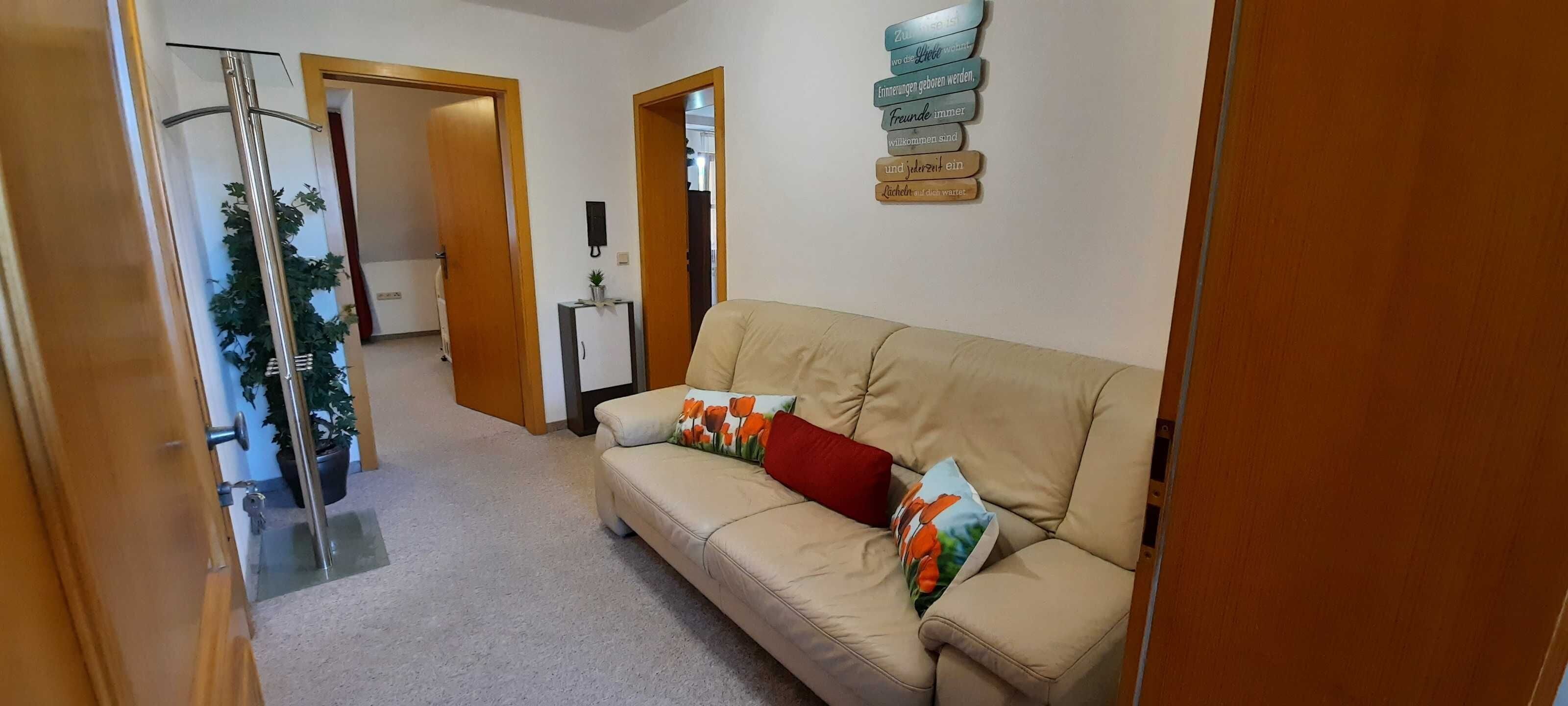 A hallway with a beige sofa, a small table, and a wall-mounted sign.