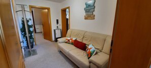 Ein Flur mit einem beigen Sofa, einem kleinen Tisch und einem an der Wand befestigten Schild.