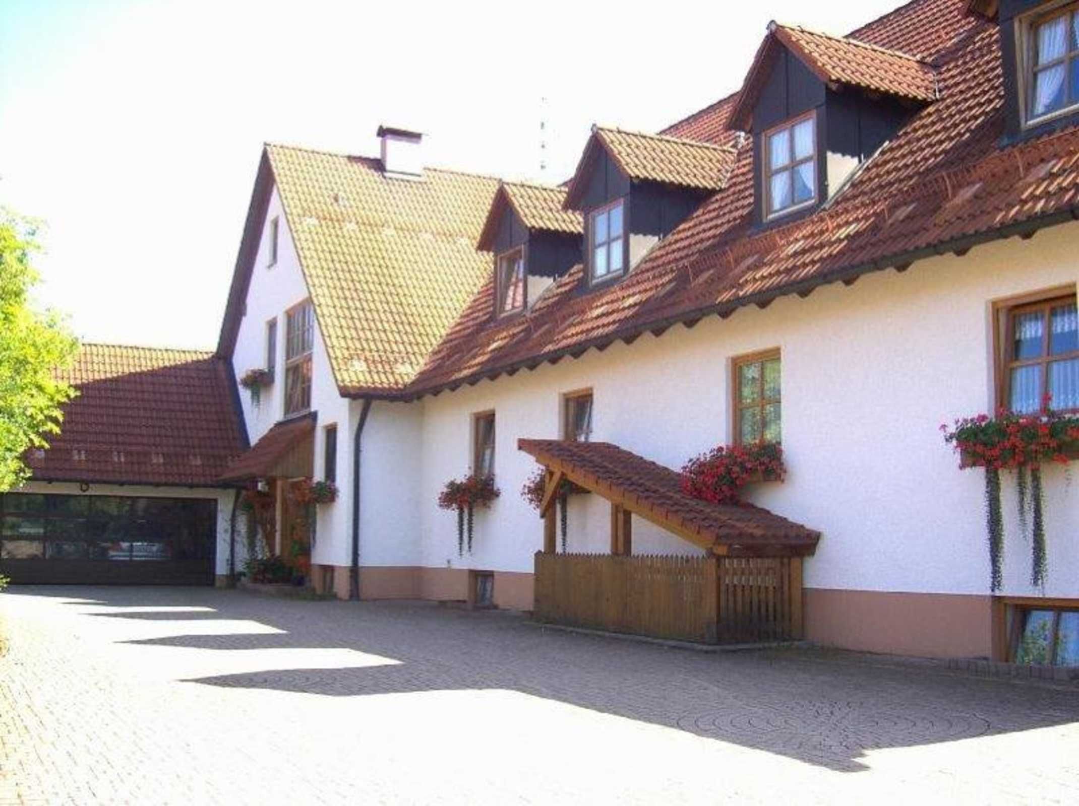 Un bâtiment traditionnel doté d’un toit en pente, de nombreuses fenêtres et d’une cour dallée.