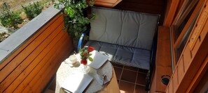 A small wooden room with a cushioned bench, a table with a white tablecloth, and a potted plant.