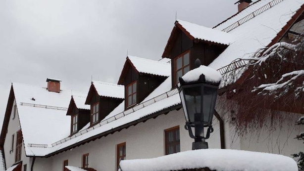 Een rij traditionele houten huizen met sneeuw bedekte daken en een lantaarnpaal.