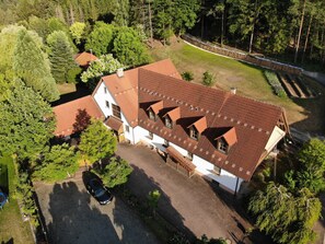 A large house with multiple roofs, surrounded by trees and a garden.