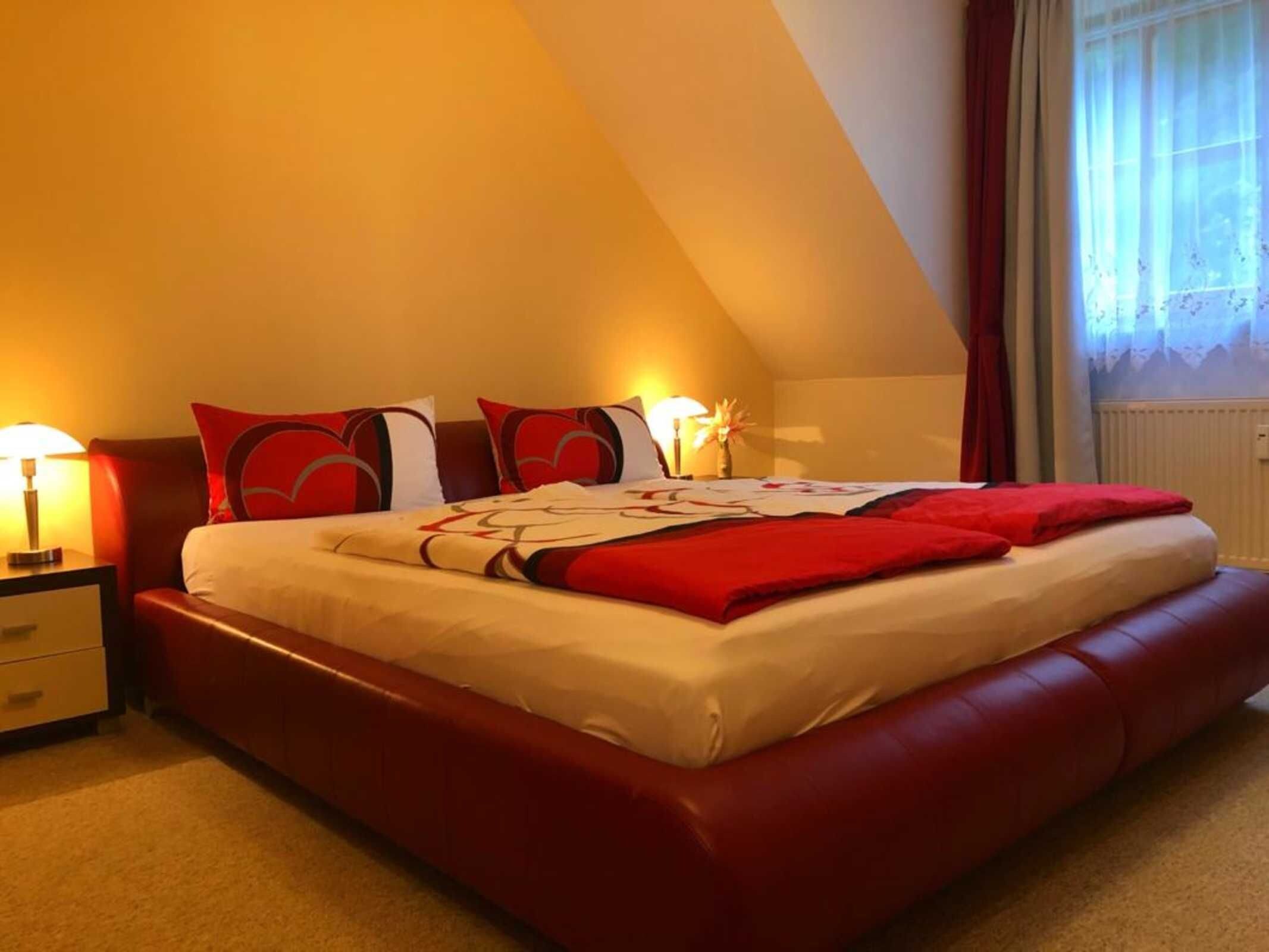 Una camera d'albergo con un letto grande, un comodino, una lampada e una finestra con tende.