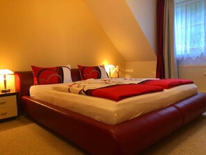 A hotel room with a large bed, a nightstand, a lamp, and a window with curtains.