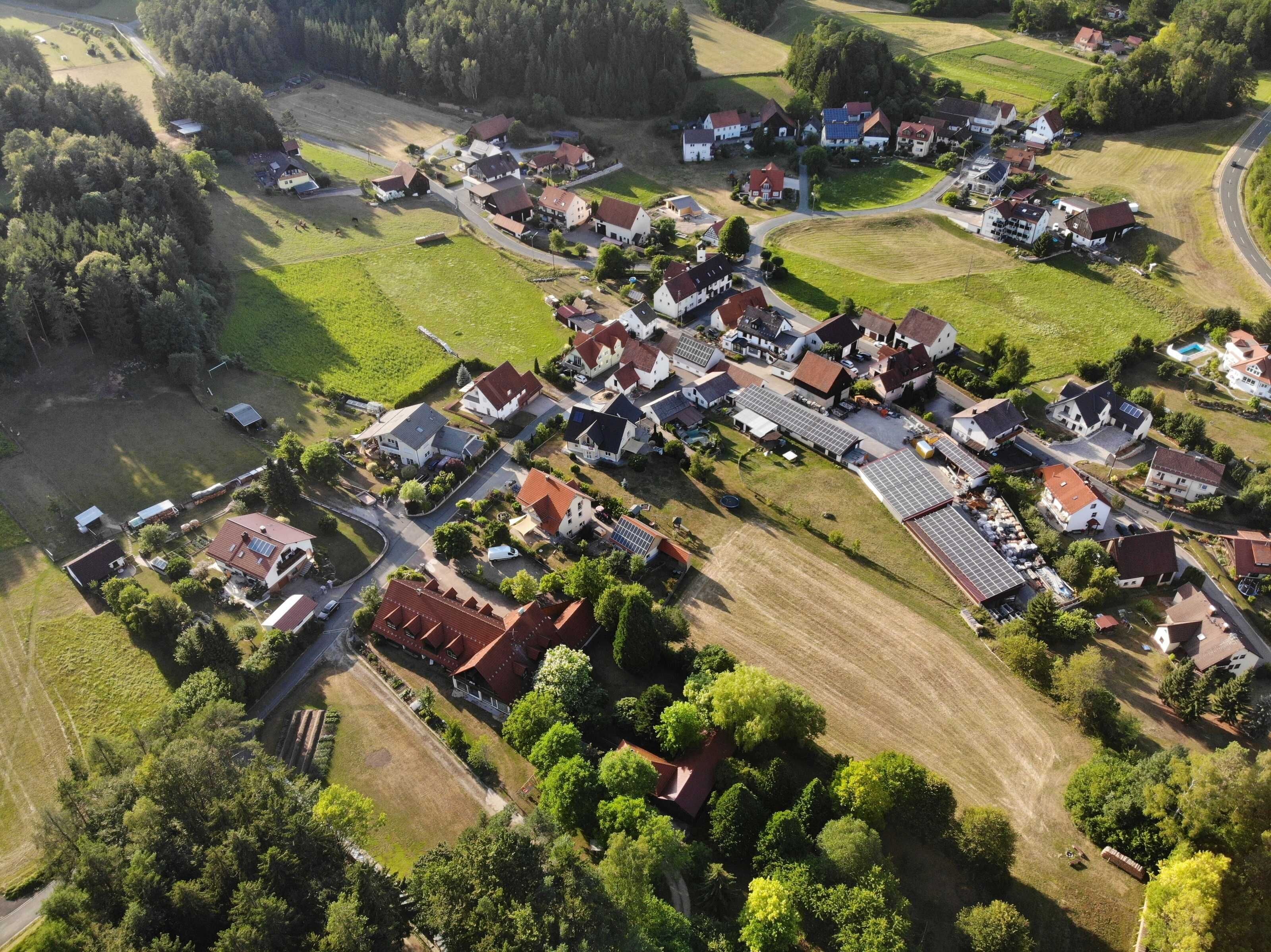 Eine Vogelperspektive auf ein Wohngebiet mit Häusern, Straßen und Grünflächen.