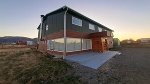 Una casa moderna de dos pisos con amplios ventanales, fachada de madera y camino de entrada de concreto.