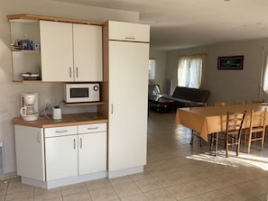 Una cocina compacta con microondas, cafetera y comedor con mesa y sillas.