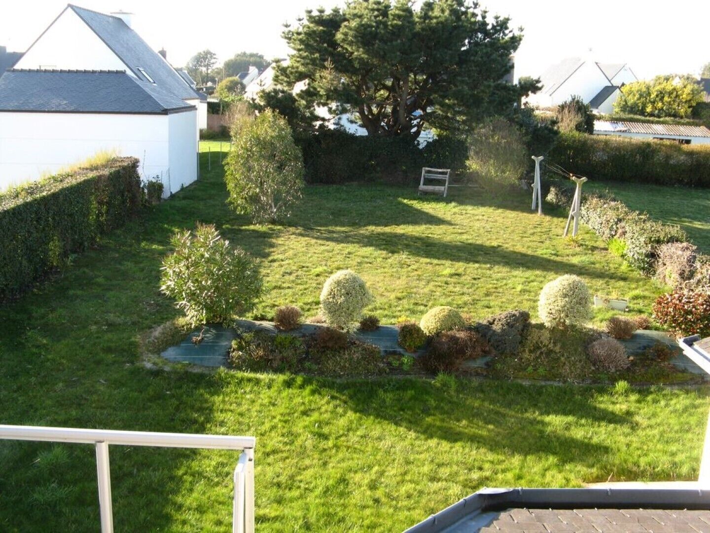 Un jardin résidentiel avec une pelouse, un petit étang et divers arbustes.