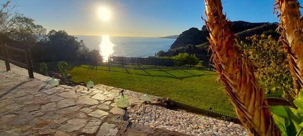 A stone pathway leading to a grassy area with a view of the sea and distant hills. - BELLA SIRENA, independent and private villa with large terraces and garden (Nerja)