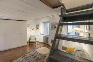 A room with a staircase, a sofa, a lamp, and a radiator.