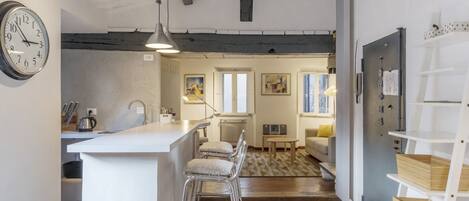 A modern kitchen with a bar area, a dining area with a sofa, and a living room with a fireplace.