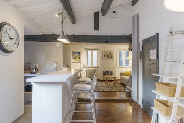 A modern kitchen with a bar area, a dining area with a sofa, and a living room with a fireplace.