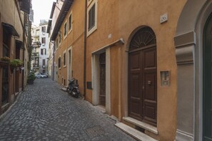 A narrow cobblestone street flanked by buildings with arched doorways and numbered windows.