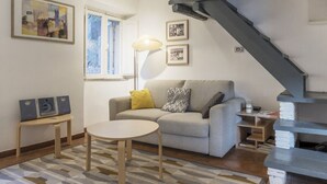 A living room with a sofa, a round table, a lamp, and a staircase. - Modern and comfortable loft equipped with every comfort. Ideal for hosting 2 people, in approximately 55 m2 of space, it is located on the third floor of an elegant period building without a lift.It is located a few minutes walk from Piazza Navona, Panth (Roma)