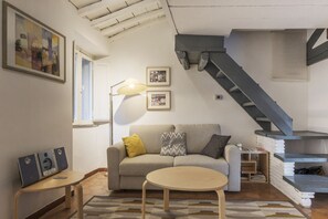 A living room with a sofa, a coffee table, a lamp, and a staircase.