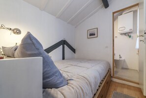 A bedroom with a bed, a bedside lamp, a framed picture, a window, and a bathroom with a sink and mirror. - Modern and comfortable loft equipped with every comfort. Ideal for hosting 2 people, in approximately 55 m2 of space, it is located on the third floor of an elegant period building without a lift.It is located a few minutes walk from Piazza Navona, Panth (Roma)