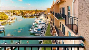 A marina with boats docked along a waterfront, adjacent to a building with balconies.