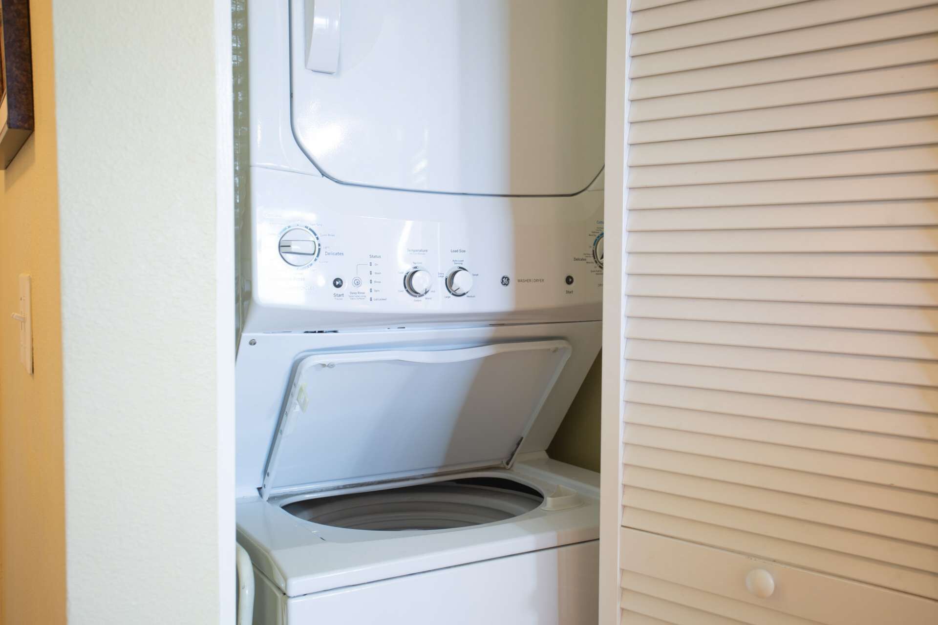 A front-loading washing machine with a control panel, a dryer, and a door.