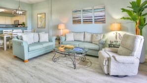 A living room with two sofas, a coffee table, and a dining area with a table and chairs.