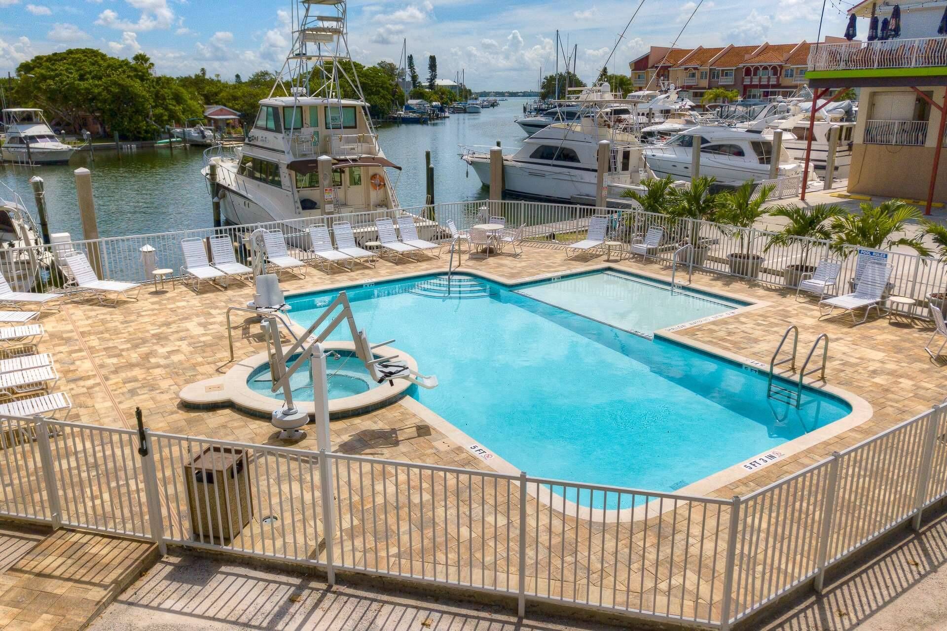 A pool area with a view of boats and a marina in the background.