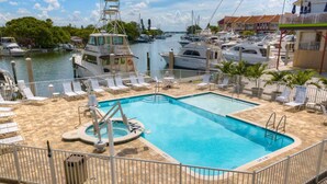 Zona de piscina con vistas a barcos y un puerto deportivo al fondo.