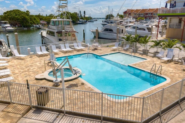 Zona de piscina con vistas a barcos y un puerto deportivo al fondo.