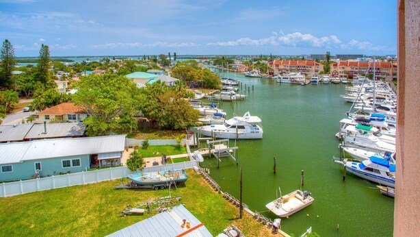 Un puerto deportivo con barcos amarrados, rodeado de edificios residenciales y vegetación.