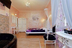 Une chambre à coucher comprenant un lit, une coiffeuse avec un miroir, une chaise, un bureau, un lustre et un téléviseur fixé au mur.
