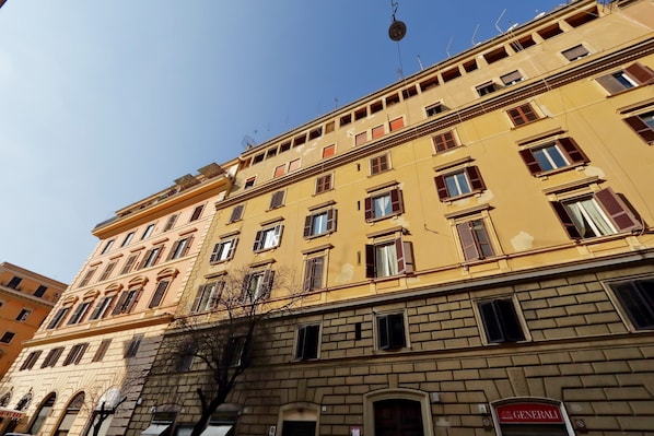 Un immeuble à plusieurs étages, doté d’une façade jaune, de nombreuses fenêtres et d’une enseigne bien visible indiquant « Generali ».