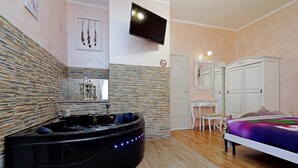 Un dormitorio con cama, televisor, tocador y bañera de hidromasaje.