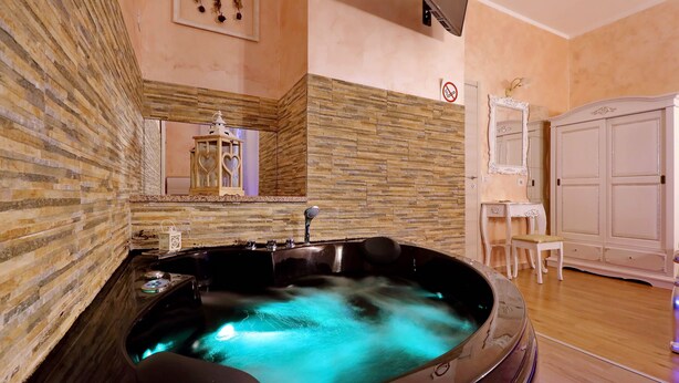 Un cuarto de spa con jacuzzi, paredes de madera, un espejo y un armario blanco.