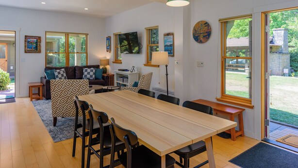 Un vaste espace de vie comprenant une grande table à manger en bois, des sièges confortables, un canapé et un téléviseur.