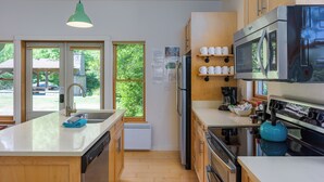 Une cuisine moderne avec des meubles en bois, un lave-vaisselle encastré, un réfrigérateur en acier inoxydable et un four à micro-ondes.