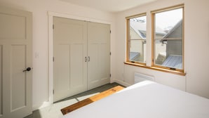 Une chambre avec un grand lit, une armoire et une fenêtre donnant sur une maison.