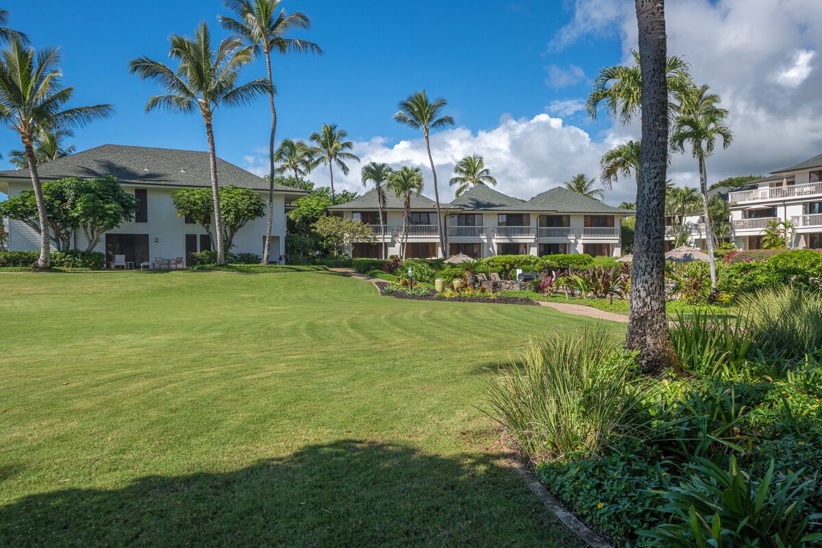 A hotel with multiple-story buildings, a well-maintained lawn, and palm trees.