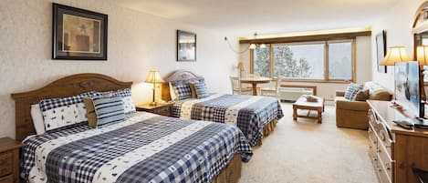 A cozy bedroom with two beds, a small table, and a sofa.