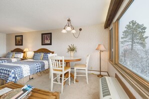 A hotel room with two beds, a dining table with chairs, a window with a view of trees, and a radiator. - Birdie's Bluff | | AC, Pool, Hot Tub, Golf & Ski (Durango)