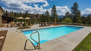 A swimming pool with lounge chairs and umbrellas, surrounded by trees and a mountain view. - The Mulligan | AC, Pool, Hot Tub, Golf & Ski (Durango)