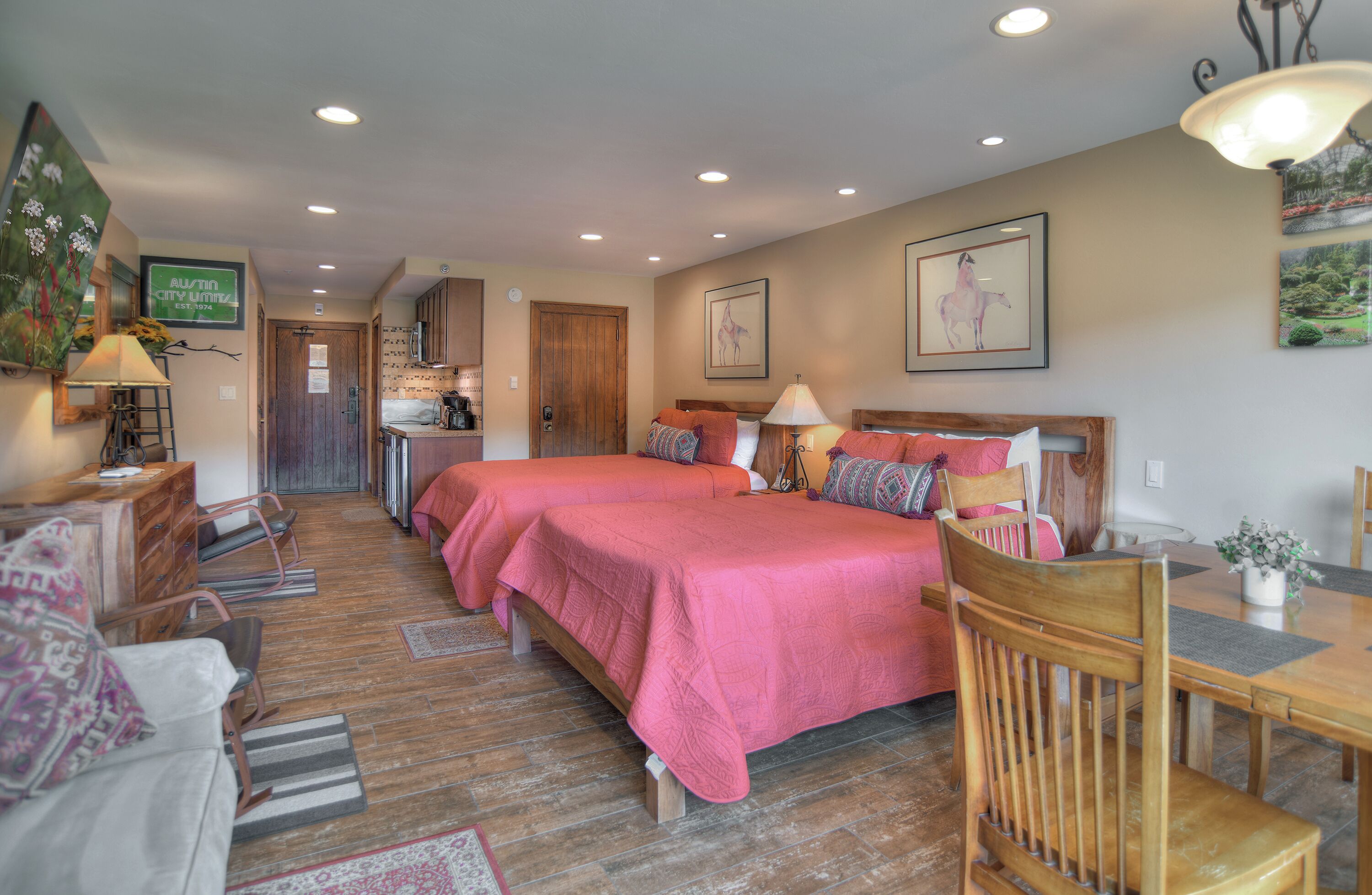 A hotel room with two beds, a dining table, a kitchen area, and a living space.