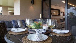 Una mesa de comedor dispuesta con platos, vasos y una vela, con vistas a una sala de estar al fondo.