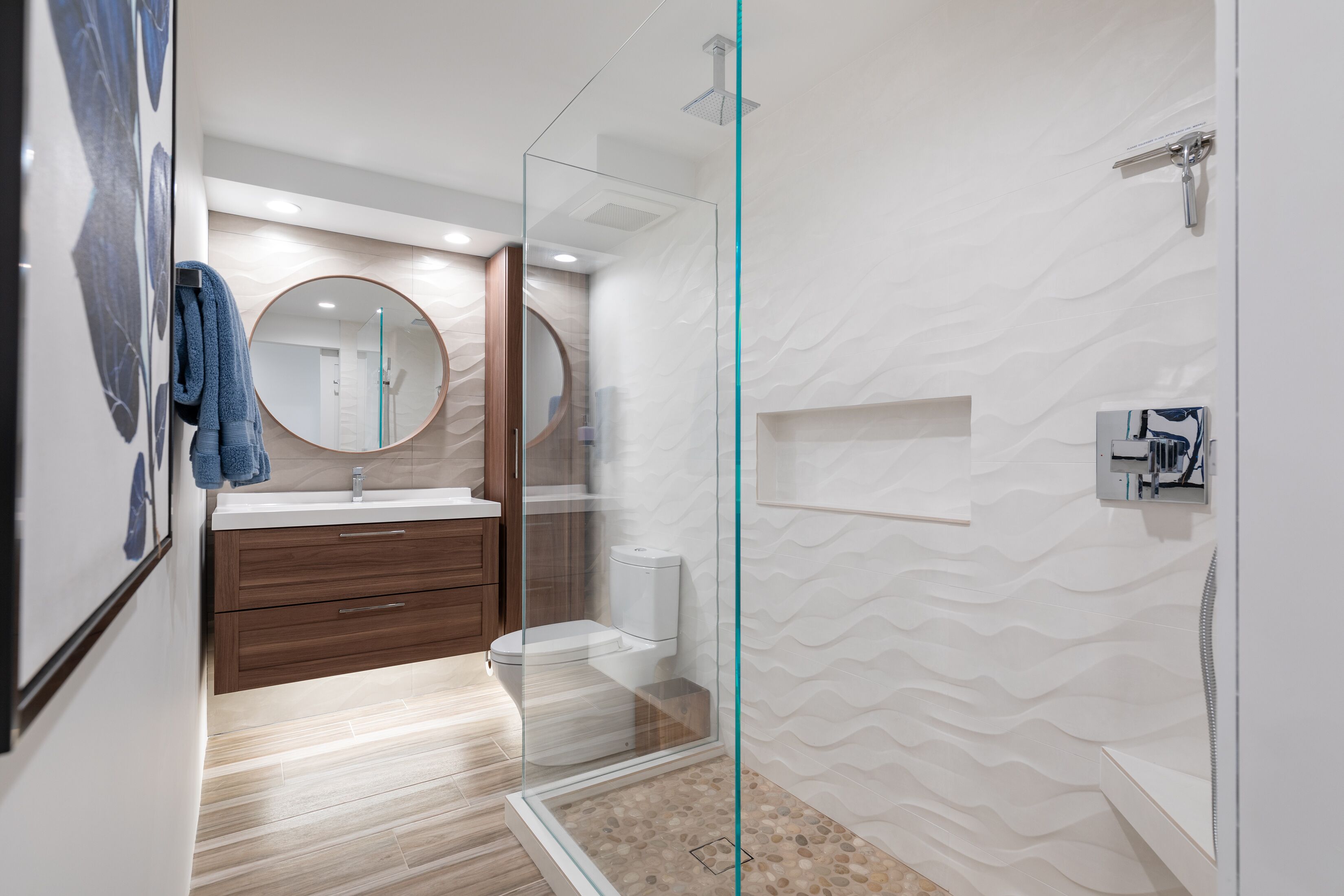 Un bagno moderno con doccia vetrata, mobile lavabo in legno e uno specchio grande.