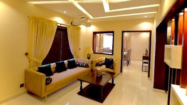 A modern living room with a sofa, coffee table, and a TV. - Golf Icon Luxury suites  (Lahore)