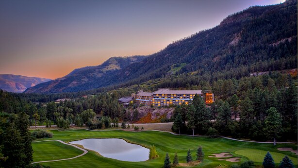 Un grand hôtel-club comprenant plusieurs bâtiments, entouré d’un magnifique parcours de golf et adossé à une chaîne de montagnes.