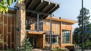 Un bâtiment moderne avec une façade en pierre, de grandes fenêtres et un espace d’entrée abrité.