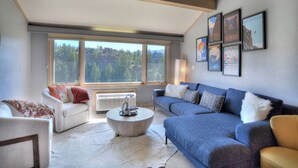 Un salon moderne avec une grande fenêtre, un canapé, une table basse et un tapis.