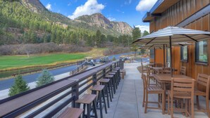 Une terrasse avec des sièges extérieurs, offrant une vue sur une rivière et des montagnes.