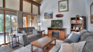 A living room with a fireplace, a sofa, a coffee table, and a bookshelf. - Whistle Stop | AC, Pool, Hot Tub, Golf & Ski (Durango)